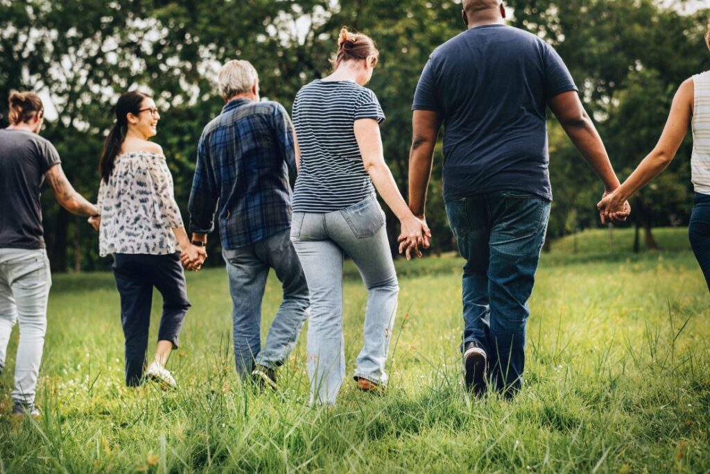 men and women walking hand in hand across a field.