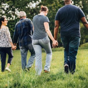 men and women walking hand in hand across a field.