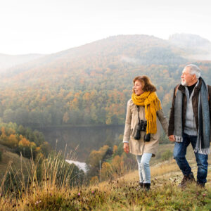 older man and woman walking during the fall in the mountains.