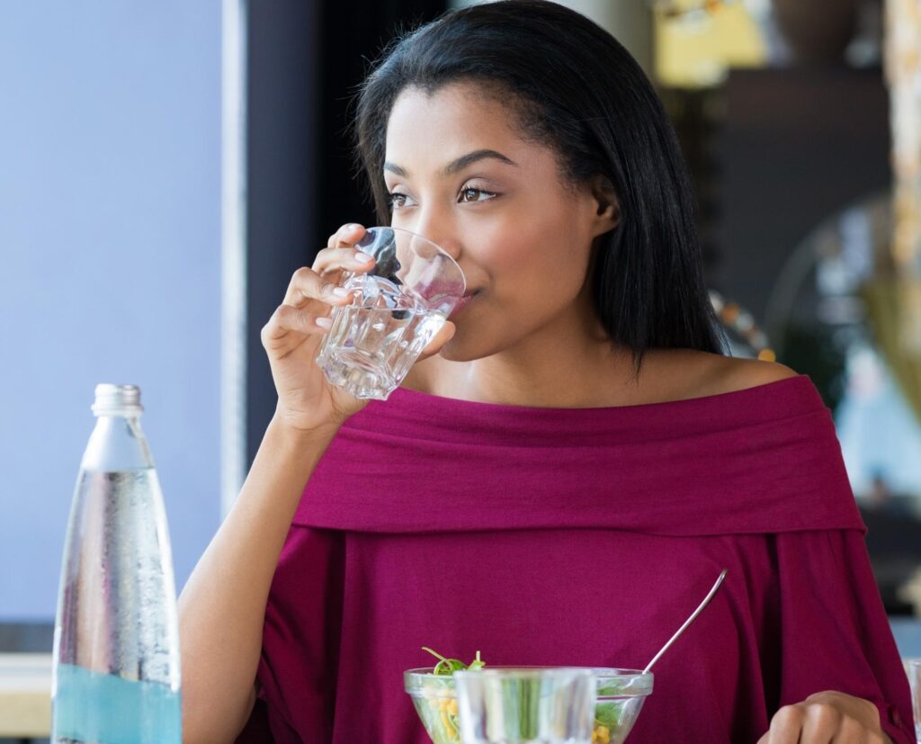 woman drinking water at restaurant.