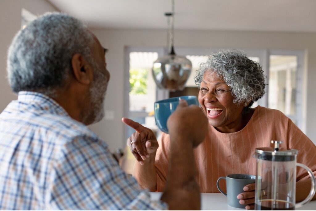 man and woman sitting at table drinking coffee and talking about incontinence.