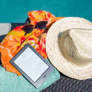 book, hat and sunglasses by the pool.