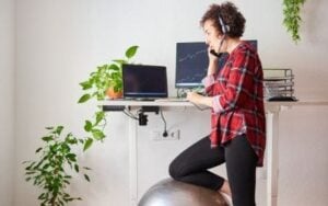 woman standing at desk with knee on exercise ball.